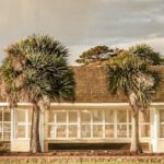 Beachfront Accommodations - Small white construction on grassland on cloudy day