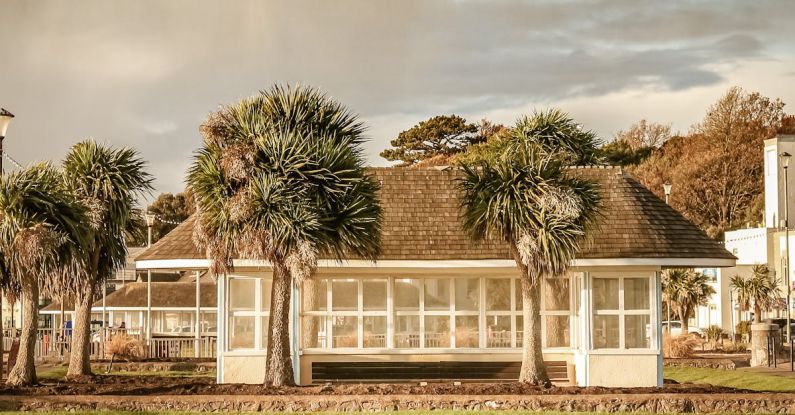 Beachfront Accommodations - Small white construction on grassland on cloudy day