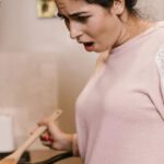 Cooking Classes - A Woman Looking at a Laptop while Cooking