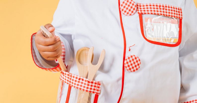 Culinary Experiences - Adorable African American child wearing uniform of cook standing with kitchen tools in studio