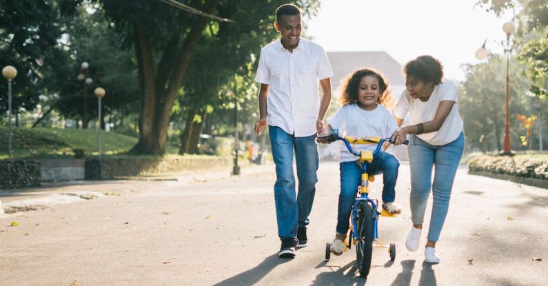 Family - Man Standing Beside His Wife Teaching Their Child How to Ride Bicycle