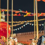 Theme Parks - Festive merry go round with carnival horses on Red Square against blurred Kremlin during New Year holidays in evening